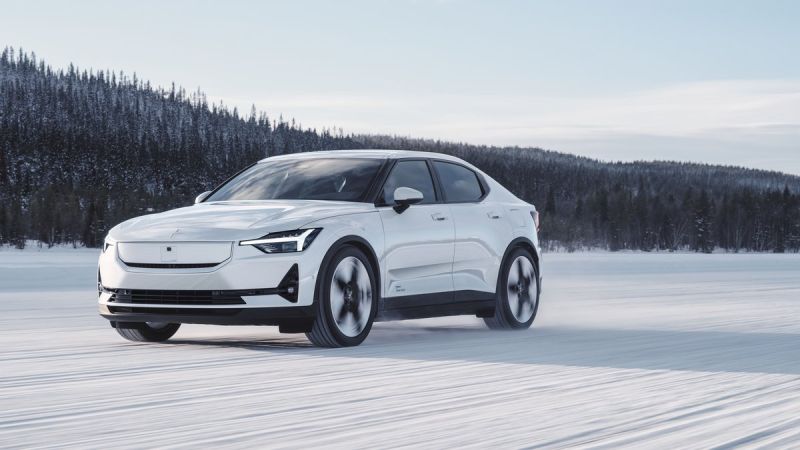 Photograph of a 2025 Polestar 2 electric sedan in a silver color, shown from the front three-quarter angle to display the vehicle's sleek profile, distinctive grille design, and headlight configuration.