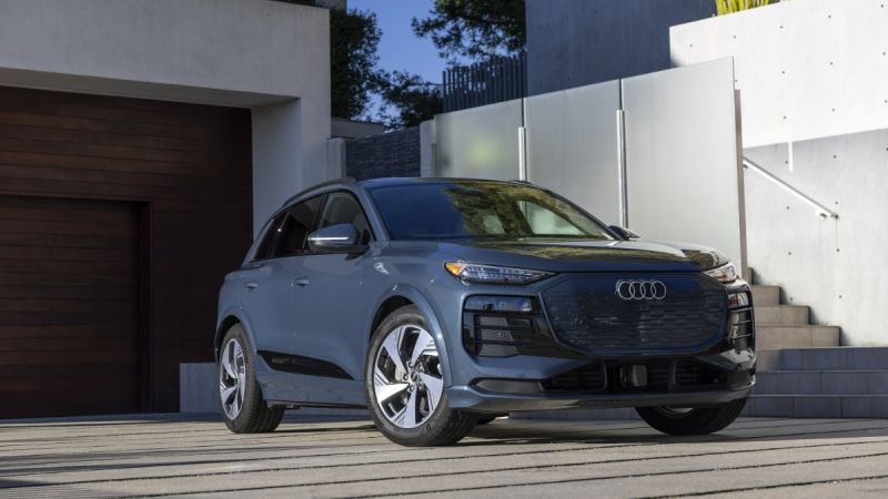 2024 Audi Q4 e-tron in metallic gray, front three-quarter view, parked on modern concrete driveway with geometric white walls.