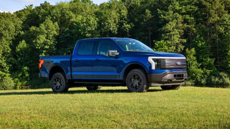 Blue Ford F-150 STX pickup truck parked on grass with forest backdrop