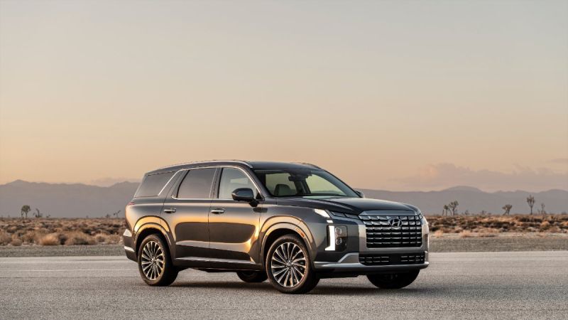 2026 Hyundai Palisade SUV in dark gray, parked on desert road at sunset with mountain silhouette