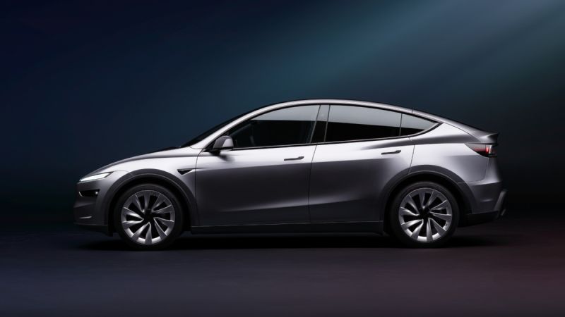 Side profile of the 2026 Tesla Model Y Juniper in gray, highlighting its sleek coupe-SUV silhouette, redesigned headlights, and aerodynamic body lines.