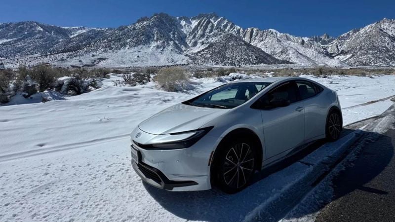 2026 Toyota Prius hybrid front three-quarter view in white driving through snowy mountain landscape