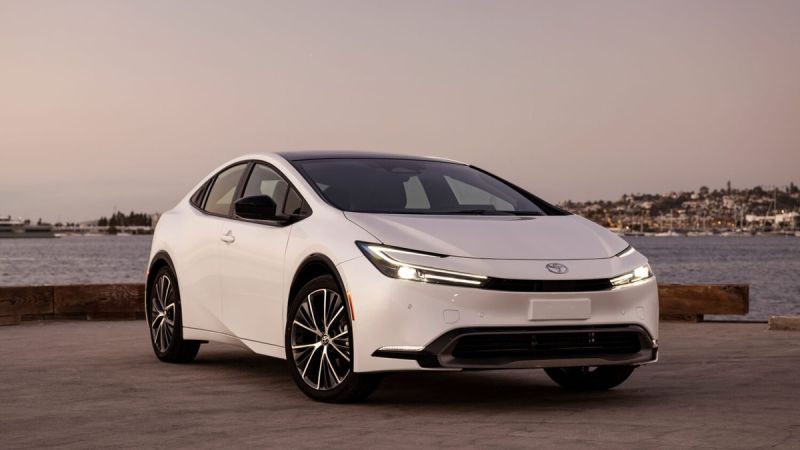 A sleek white Toyota car parked by a tranquil waterfront at sunset, showcasing modern design and elegant features.