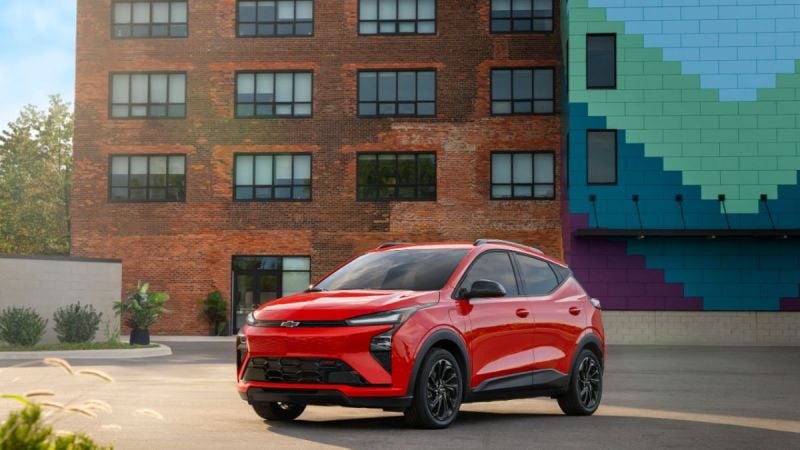 2027 Chevrolet Bolt EV red compact electric SUV front three-quarter view parked in urban setting