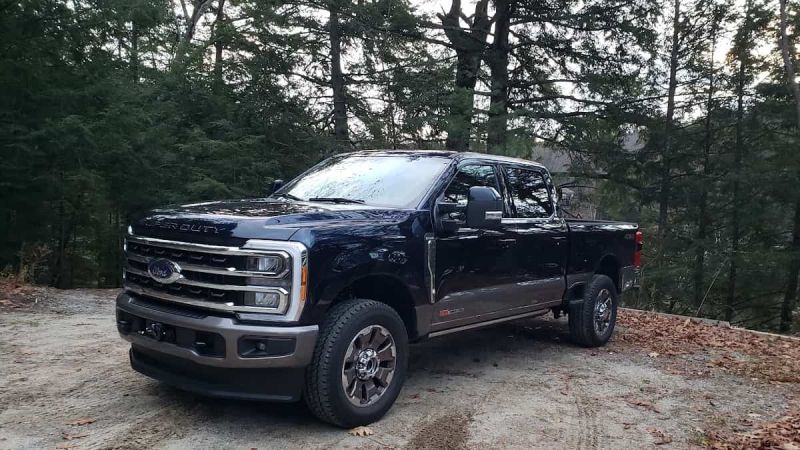 Image shows a Ford F-250 in blue and silver against a backdrop of a wooded area.