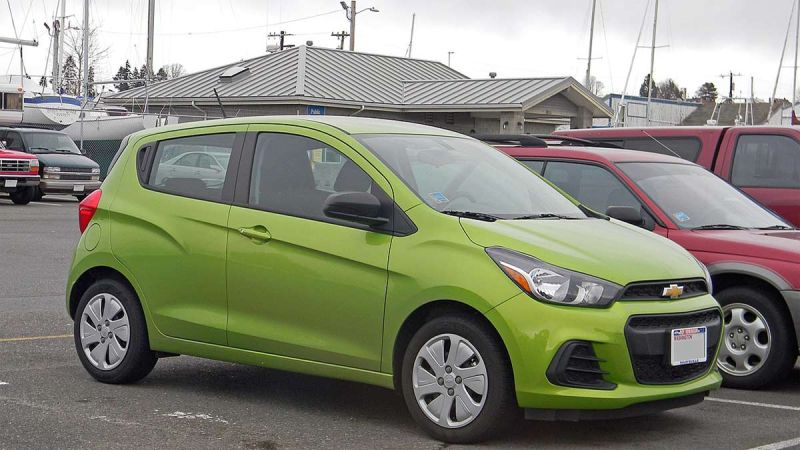 A lime green colored Chevrolet Spark sits in a parking lot.