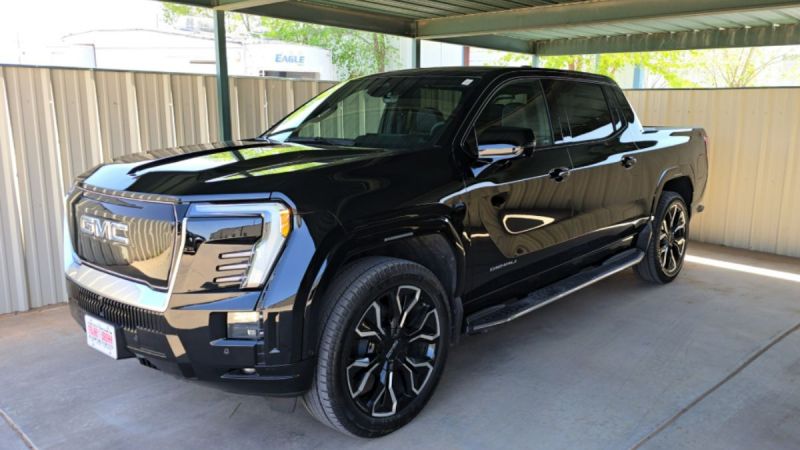 Sleek black GMC Sierra Denali pickup truck with premium wheels parked under metal carport