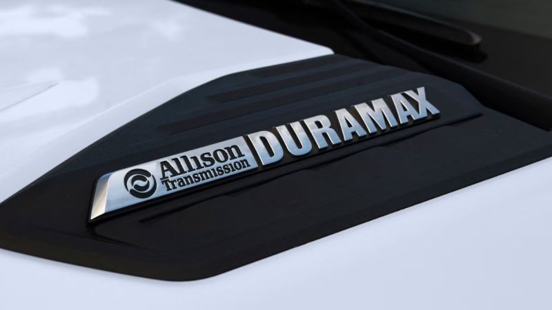 Close-up of a Chevrolet Silverado hood with "Allison Transmission" and "Duramax" in shiny silver letters on a black accent, conveying strength and durability.