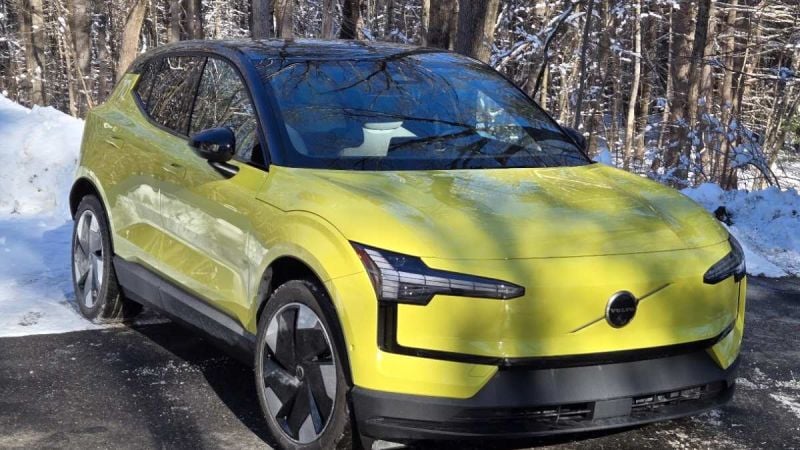 A Volvo EX30 looks sporty in yellow against a winter backdrop