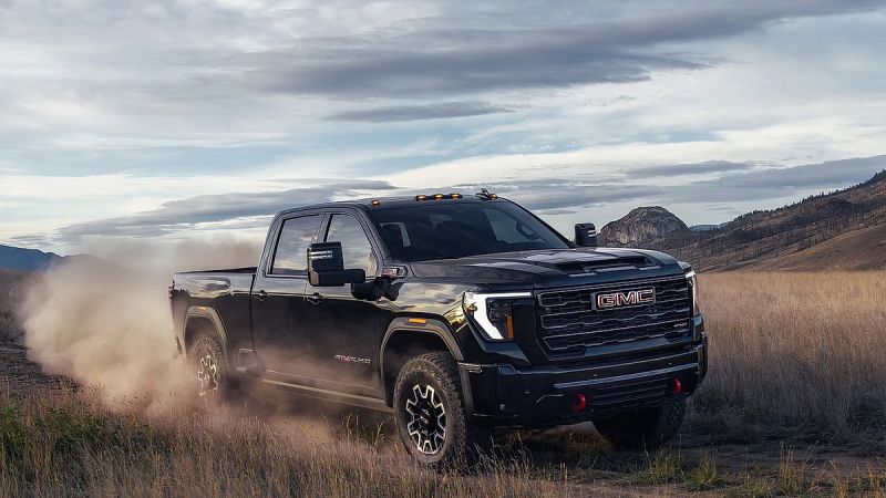 GMC Sierra HD AT4X heavy duty pickup truck driving off road kicking up dust