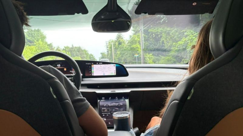 Two passengers in the front of a Lucid Air, engaged in conversation while driving on the road