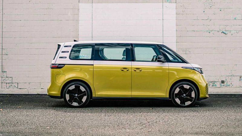 A yellow Volkswagon ID Buzz sits parked and readym with a white brick wall in the background