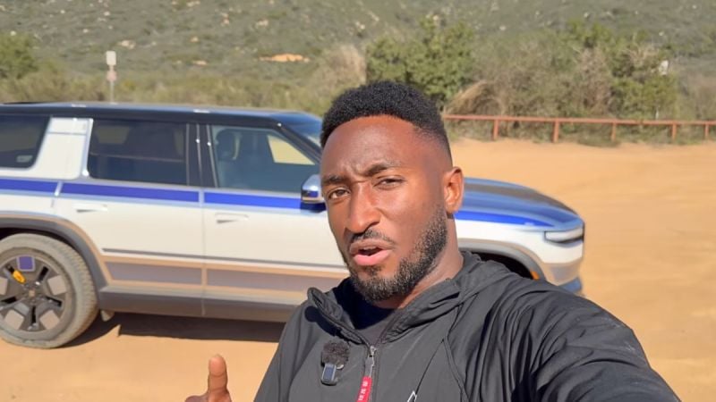 Marques Brownlee points to the camouflaged Rivian R2