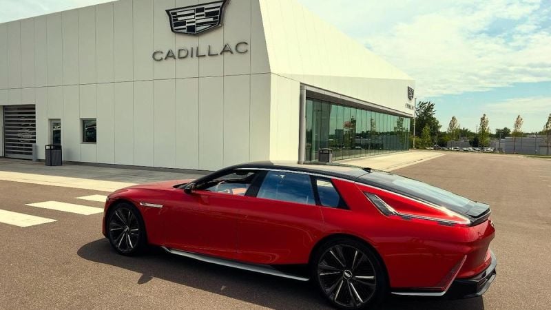 A red 2026 Cadillac Celestiq parked outside a modern dealership showcasing the brand's logo against a clear sky.