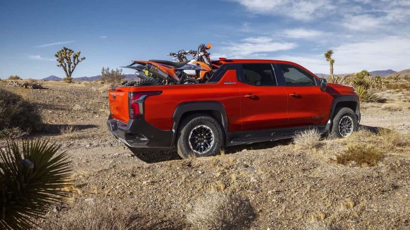 Red 2026 Chevy Silverado EV Trail Boss with motorcycles in bed