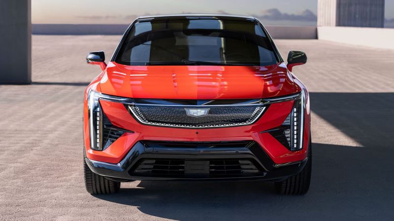 Front view of a sleek red Cadillac electric SUV showcasing modern design with sharp lines and distinctive LED headlights.