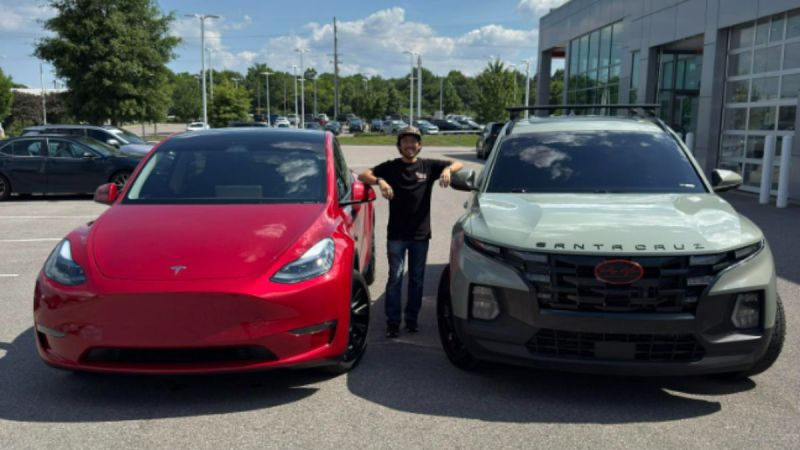Riley is seen standing and smiling between a red Tesla and a sage gray Hyundai Santa Cruz in a car dealership lot on a sunny day, conveying excitement and choice.