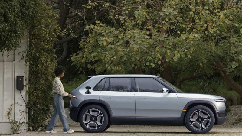 Rivian R2 Side profile, gray with one man walking towards it