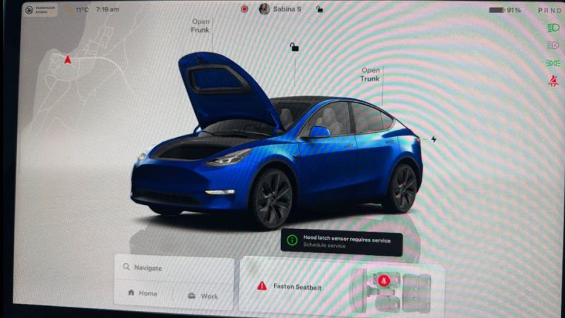 Blue Tesla Model Y with open hood and trunk, displayed on vehicle interface screen with service notification