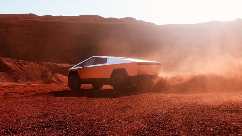 Tesla Cybertruck accelerating through dusty desert terrain with rugged mountains in background