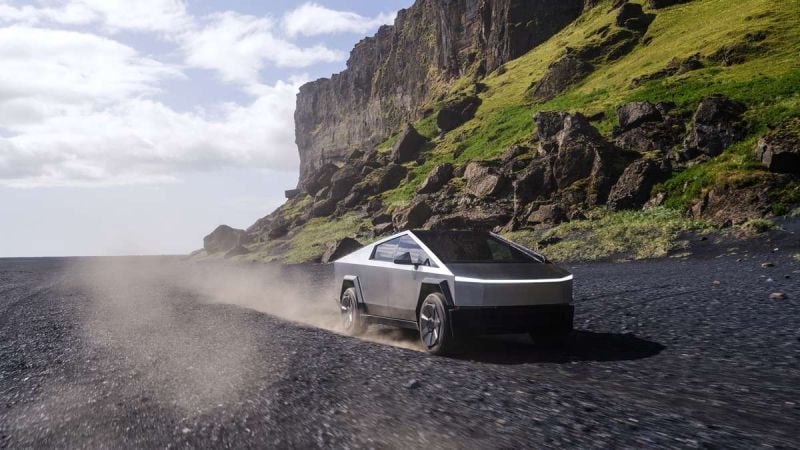 Tesla Cybertruck driving on rocky volcanic terrain with steep cliffs and dust trail