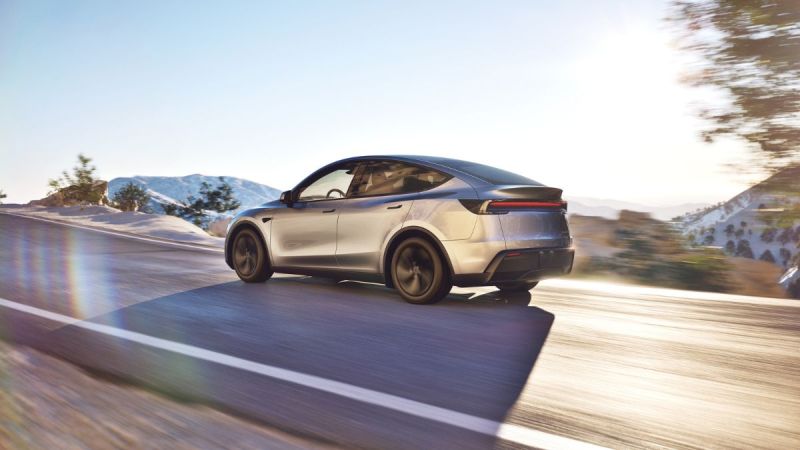 Silver electric SUV driving on mountain road with snowy peaks and blurred motion effect