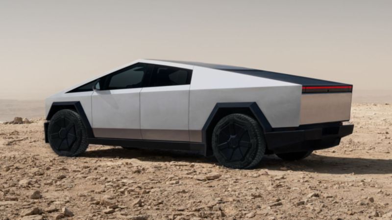 Futuristic looking silver Tesla Cybertruck with angular design and dark windows on a rocky desert landscape. The vehicle conveys a sleek, modern, and rugged tone.