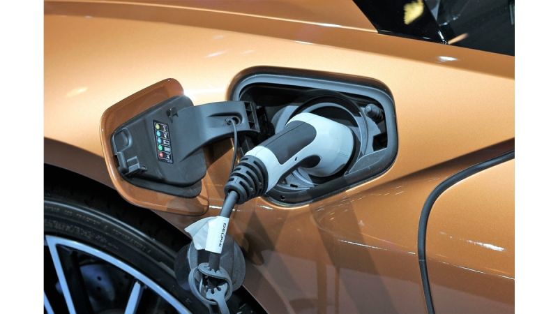 Image showing a gold BMW i8 charging port with cable attached.