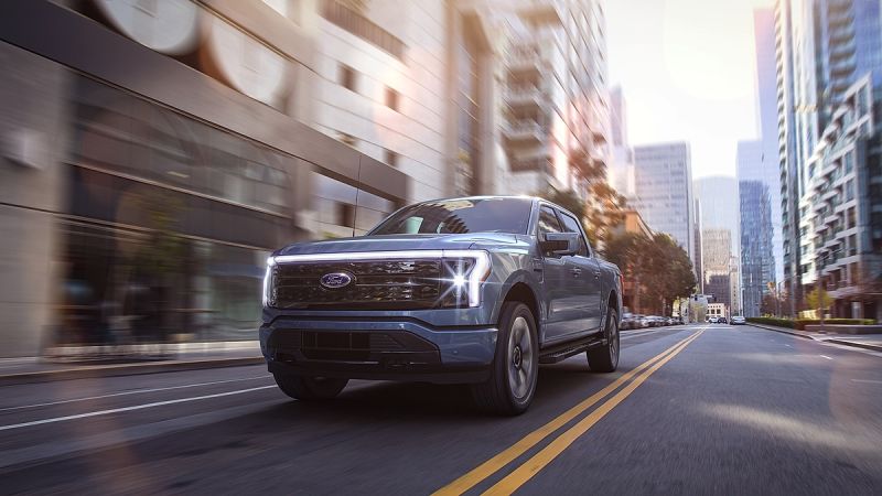 Ford F-150 Lightning electric pickup truck driving through a modern city street.