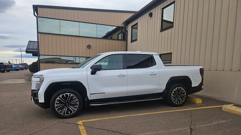 White GMC Sierra EV parked in lot side profile view