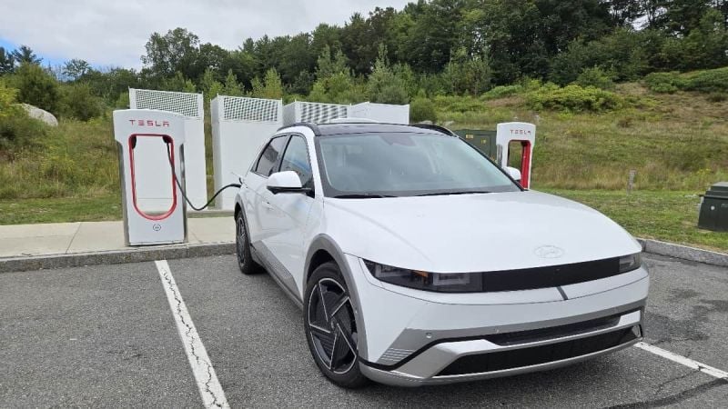 A 2026 Hyundai Ioniq 5 Limited charges at a Tesla Supercharger occupying two spaces
