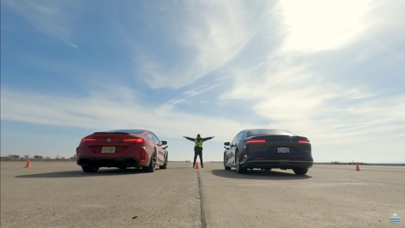A red BMW M8 Competition and Edmunds' long-term Lucid Air Grand Touring line up at the start line for a drag race.