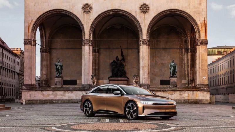 Image of a gold Lucid Air Dream Edition parked in front of a historic building ahead of the brand's first European Studio opening in Munich.