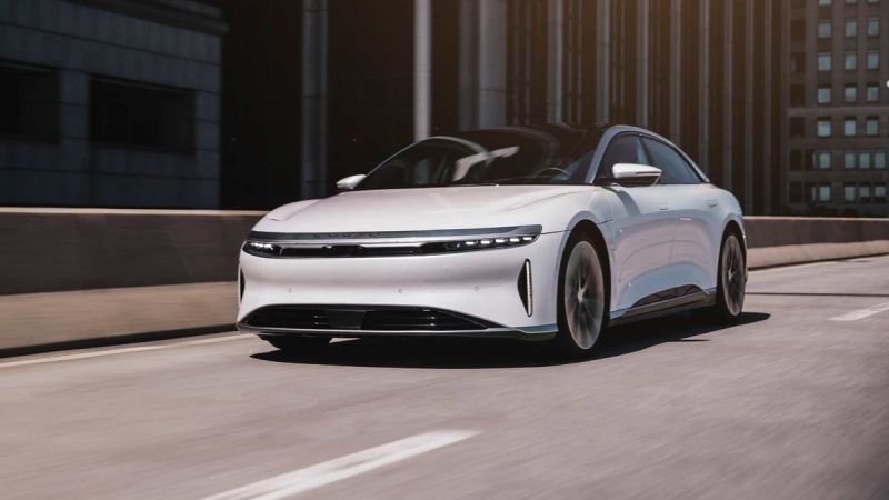 Image of a white Lucid Air Grand Touring driving on an elevated highway in a city.