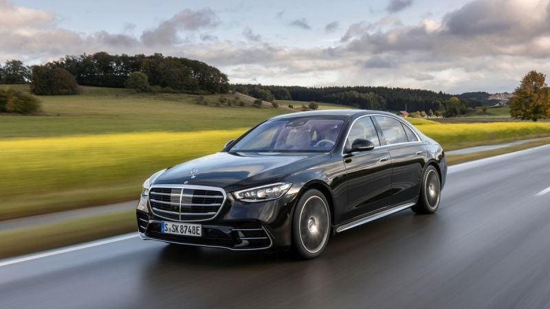 A Mercedes-Benz S-Class is pictured driving in lush green scenery.