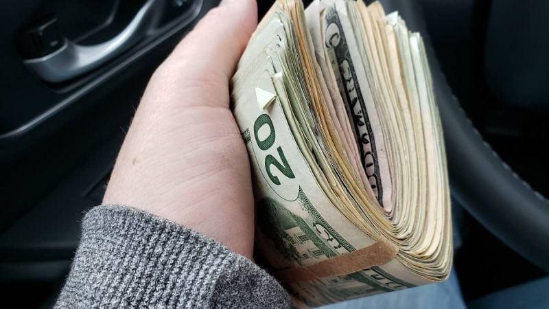 A car shopper holds a fat stack of bills in his hand