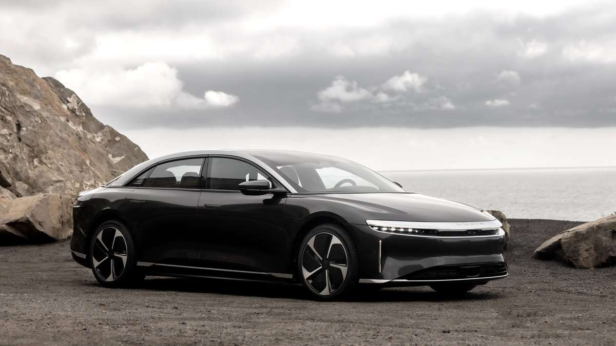 Photograph of a 2025 Lucid Air Touring electric vehicle in a two-tone color scheme, captured from a low angle that showcases the front three-quarter view of the car.