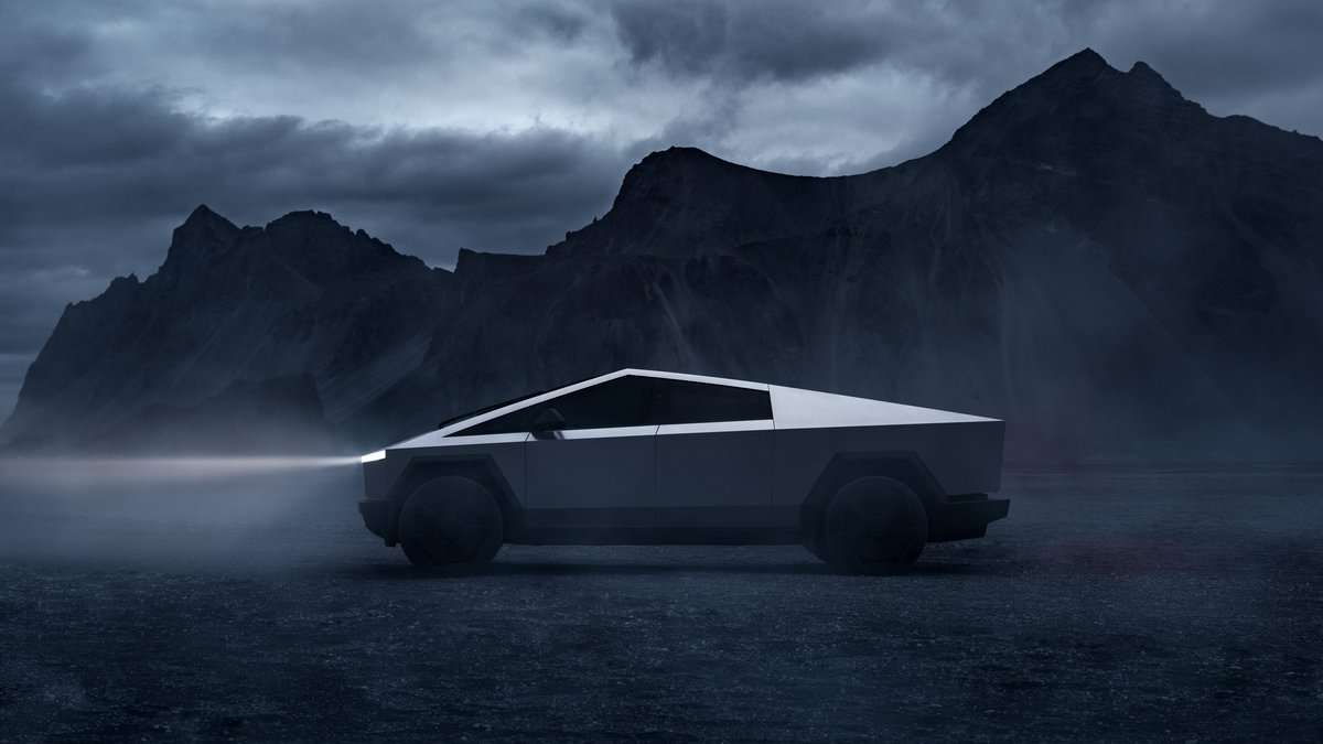 Side view of Tesla Cybertruck in a misty mountain setting, emphasizing angular stainless steel design and rugged styling.