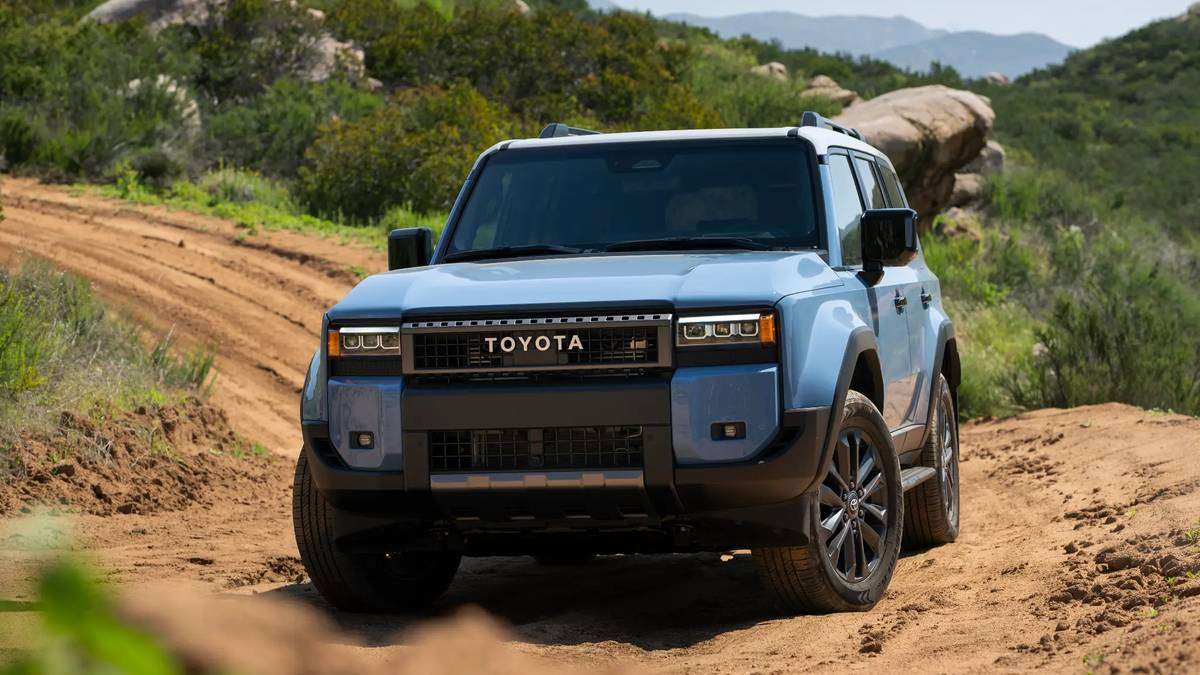 2026 Toyota Land Cruiser heritage blue driving on dirt trail through rocky mountain terrain