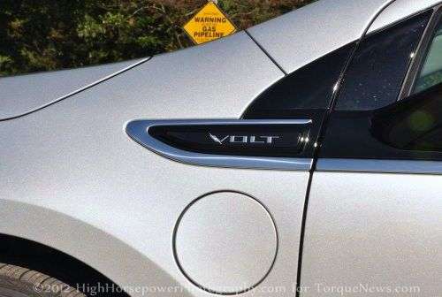 The Chevy Volt charging door and logo with a gas line sign in the background