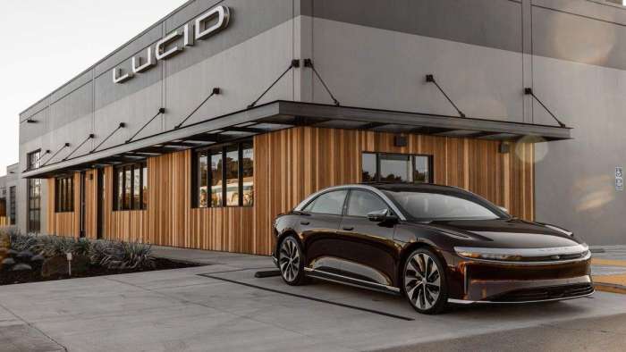 Image showing a copper colored Lucid Air parked outside the wood-clad sales studio in Millbrae California.