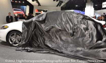 The cover being pulled off of the 2013 Dodge Dart