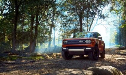 An orange Scout Traveler takes the path less traveled, a dirt road through the forest
