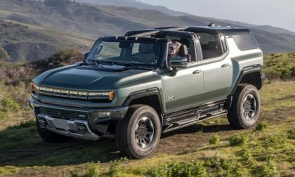 GMC Hummer EV SUV driving on rugged mountain terrain with open removable roof panels