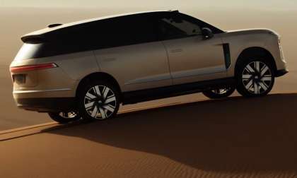 ​A side profile view of a champagne-colored NIO ES8 luxury electric SUV parked on a sandy desert dune.