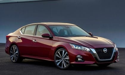Deep red 2019 Nissan Altima sedan, angled front view with sleek profile against dark gray background