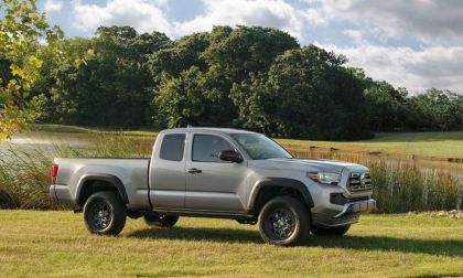 White Toyota Tacoma parked near a lake, front view of midsize pickup truck