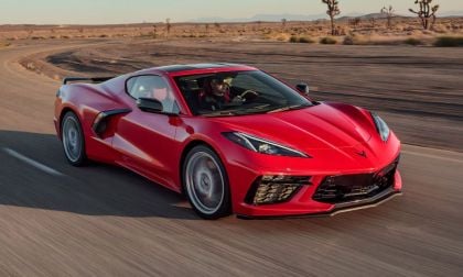 Red 2020 Chevrolet C8 Corvette driving on an open desert highway shown from a front three-quarter angle