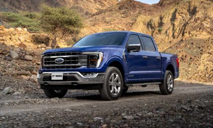 A blue 2021 Ford F-150 pickup truck shown from a front three-quarter angle, positioned against a rocky desert mountain backdrop.