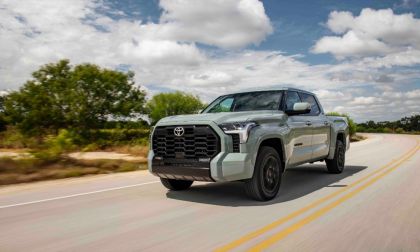 Sage green 2022 Toyota Tundra pickup truck driving on winding rural highway with cloudy blue sky and trees